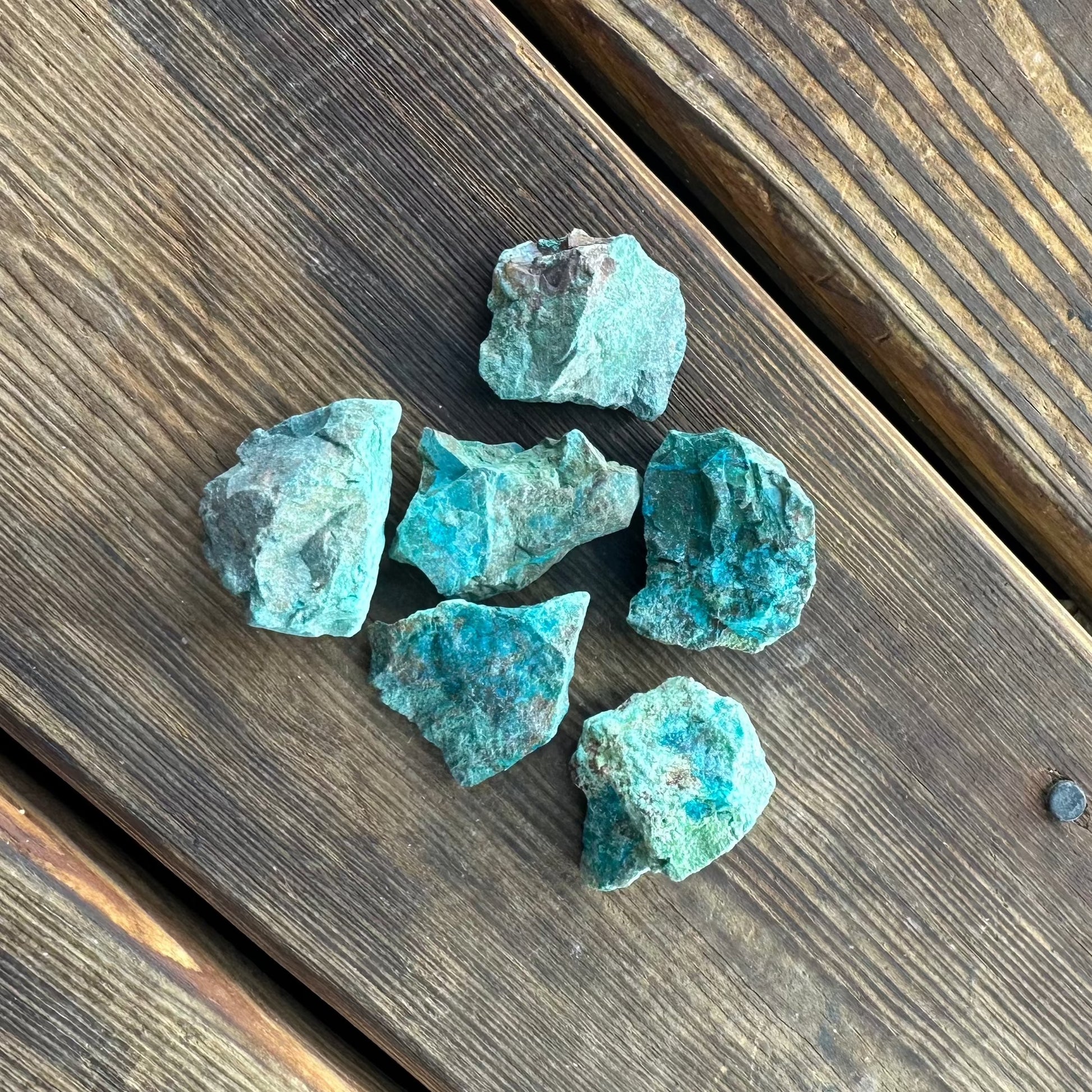 blue green raw pieces of the gemstone chrysocolla on a wooden background 