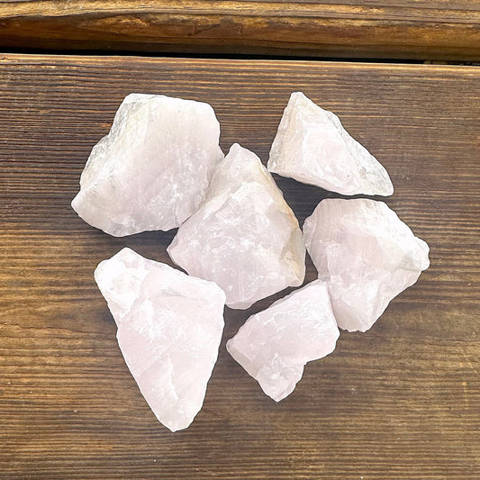 pink marbled chunks of raw Mangano calcite in a pile on a wooden background